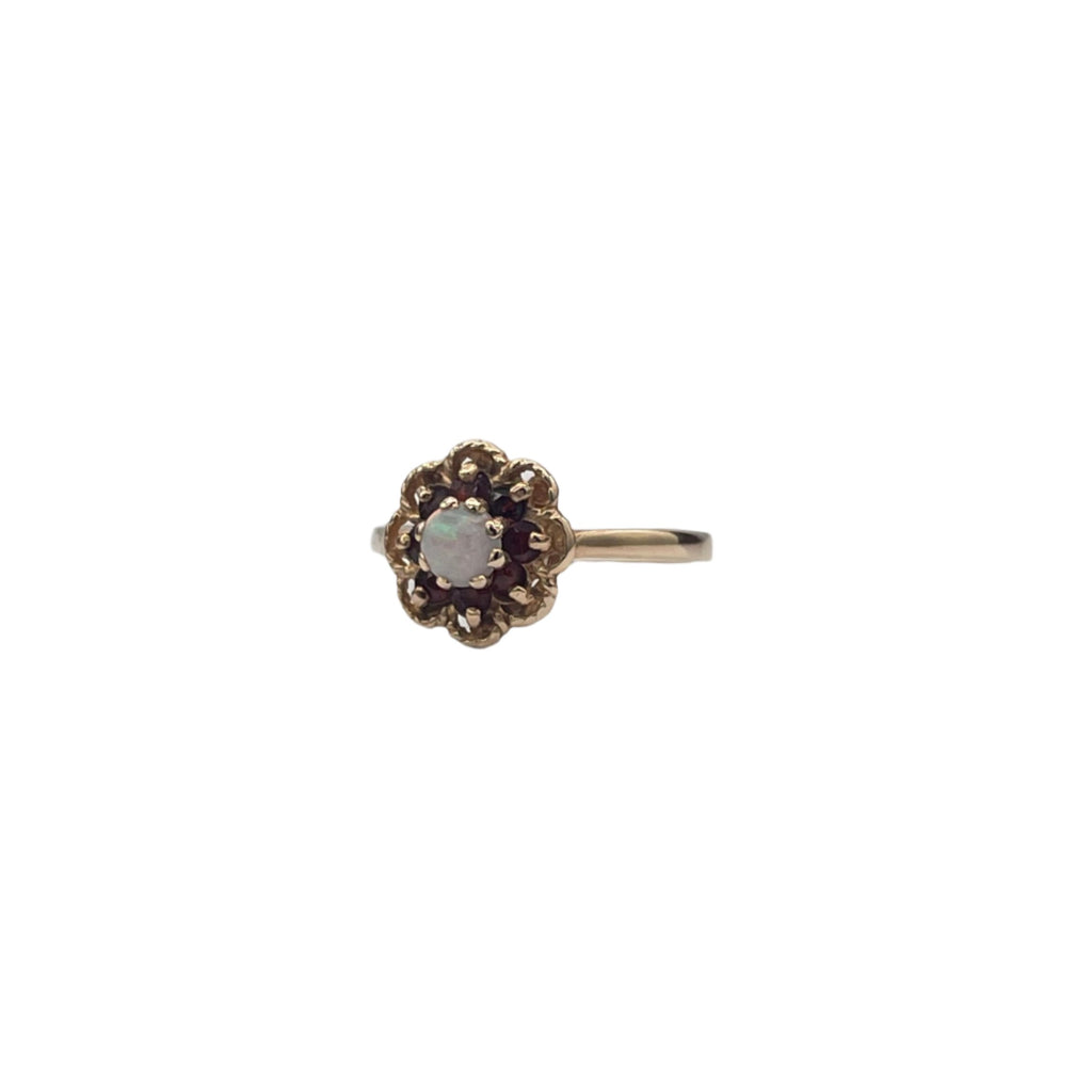 Lovely 14K yellow gold ring. A beautiful opal is set in the heart of the flower and 8 small garnets serve as petals in an openwork decor.